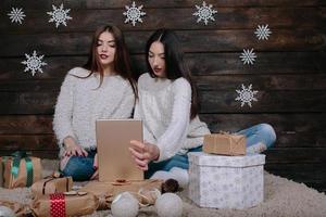 duas lindas garotas com um tablet, entre presentes foto