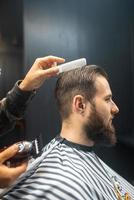 mestre em barbearia faz corte de cabelo masculino com máquina de cortar cabelo foto