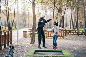 mãe e filha pulando juntos no trampolim no parque outono foto