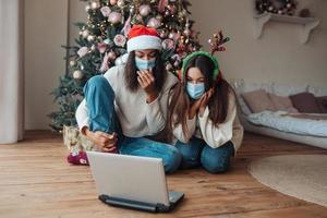 duas garotas ao falar com um amigo online no laptop foto