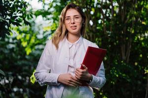 jovem engenheiro agrônomo trabalhando em estufa. jovem cientista feminina olhando para a câmera foto