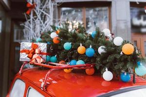 carro retrô vermelho com um abeto de árvore de natal amarrado ao telhado. foto