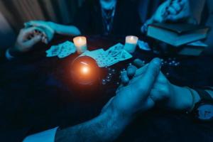 as pessoas dão as mãos da noite à mesa com velas foto