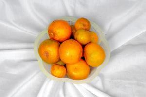 laranja fresca com folhas isoladas em fundo de pano branco foto