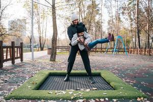 mãe e filha pulando juntos no trampolim no parque outono foto