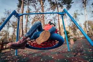 menina criança feliz no balanço. criança brincando no pacote de outono. foto