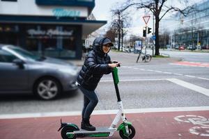 bela jovem montando uma scooter elétrica, estilo de rua foto