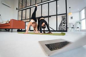duas mulheres encantadoras de esportes, fazem poses de ioga, exercícios em casa foto