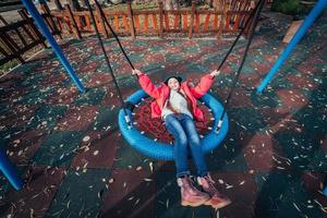 menina criança feliz no balanço. criança brincando no pacote de outono. foto