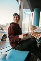 retrato de homem sentado em um café, lendo jornais e tomando café foto