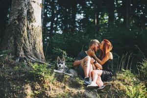 lindo casal sentado em uma floresta perto da árvore foto