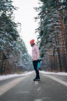 skatista em pé na estrada no meio da floresta, cercado por neve foto
