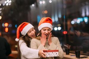 a garota dá um presente para sua amiga no caffe foto