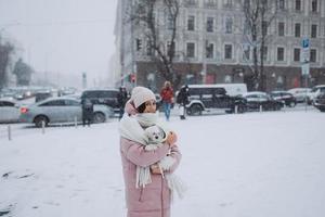 menina com um cachorro nos braços, a neve está caindo foto