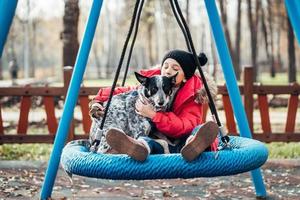 menina criança feliz no balanço. menina em um balanço abraça seu cachorro. foto