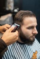 mestre em barbearia faz corte de cabelo masculino com máquina de cortar cabelo foto