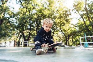 jovem sentado no parque em um skate. foto