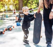 garotinho carrega um grande skate lá fora foto