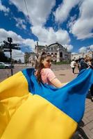 jovem carrega a bandeira da ucrânia tremulando atrás dela foto