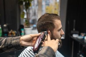 mestre em barbearia faz corte de cabelo masculino com máquina de cortar cabelo foto