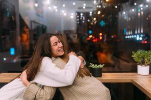 retrato de amigos jovens bonitos felizes abraçando uns aos outros no caffe. foto