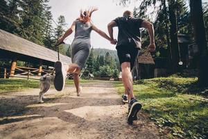 casal corre na estrada na natureza com cachorro foto