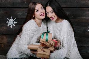duas lindas garotas oferecem presentes para a câmera foto