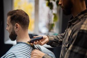 mestre em barbearia faz corte de cabelo masculino com máquina de cortar cabelo foto