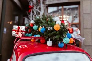 carro retrô vermelho com um abeto de árvore de natal amarrado ao telhado. foto