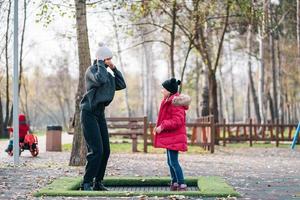 mãe e filha pulando juntos no trampolim no parque outono foto