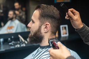 mestre em barbearia faz corte de cabelo masculino com máquina de cortar cabelo foto