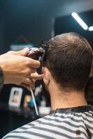 mestre em barbearia faz corte de cabelo masculino com máquina de cortar cabelo foto