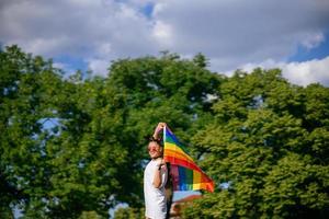 jovem acenando a bandeira do orgulho lgbt no parque. foto