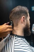 mestre em barbearia faz corte de cabelo masculino com máquina de cortar cabelo foto