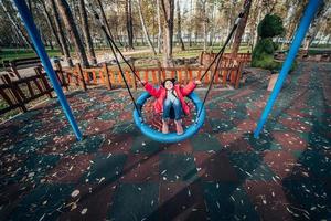 menina criança feliz no balanço. criança brincando no pacote de outono. foto