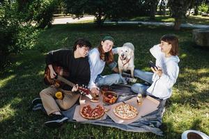 companhia de belos jovens e cachorro almoçando ao ar livre. foto