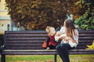 mãe e duas filhas descansam em um banco foto