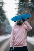 skatista em pé na estrada no meio da floresta, cercado por neve foto