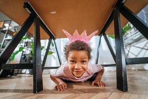 menina está jogando debaixo da língua da mesa na câmera foto