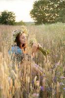 linda garota andando no campo no verão com flores silvestres. foto