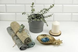 toalhas de algodão de cor neutra com um ramo de eucalipto sobre eles estão sobre uma mesa em um banheiro moderno foto