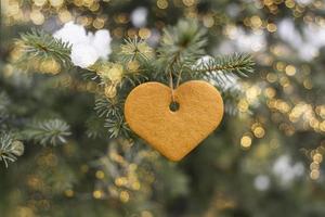 um biscoito no coração pendurado na árvore com luzes bokeh foto