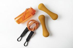 diferentes equipamentos coloridos para exercícios de fitness e esporte halteres e expansores laranja, bolas de fitness e bandas deitadas sobre um fundo branco foto