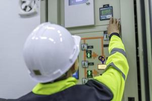 homem engenheiro elétrico verificando a tensão no gabinete de distribuição de energia na sala de controle, manutenção preventiva anualmente, eletricista tailandês trabalhando na empresa foto