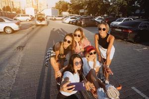 cinco meninas se divertem com um carrinho de supermercado em um estacionamento foto