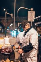 velho cozinhando salsichas na rua foto