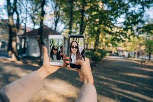 linda jovem tem nas mãos dois smartphones foto