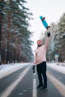 skatista em pé na estrada no meio da floresta, cercado por neve foto