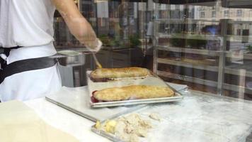 um homem prepara um strudel de maçã para venda. esfregando com pincel foto