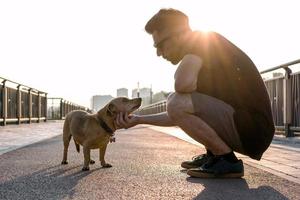 jovem bonito está andando com seu cachorro de manhã na rua vazia da cidade. foto